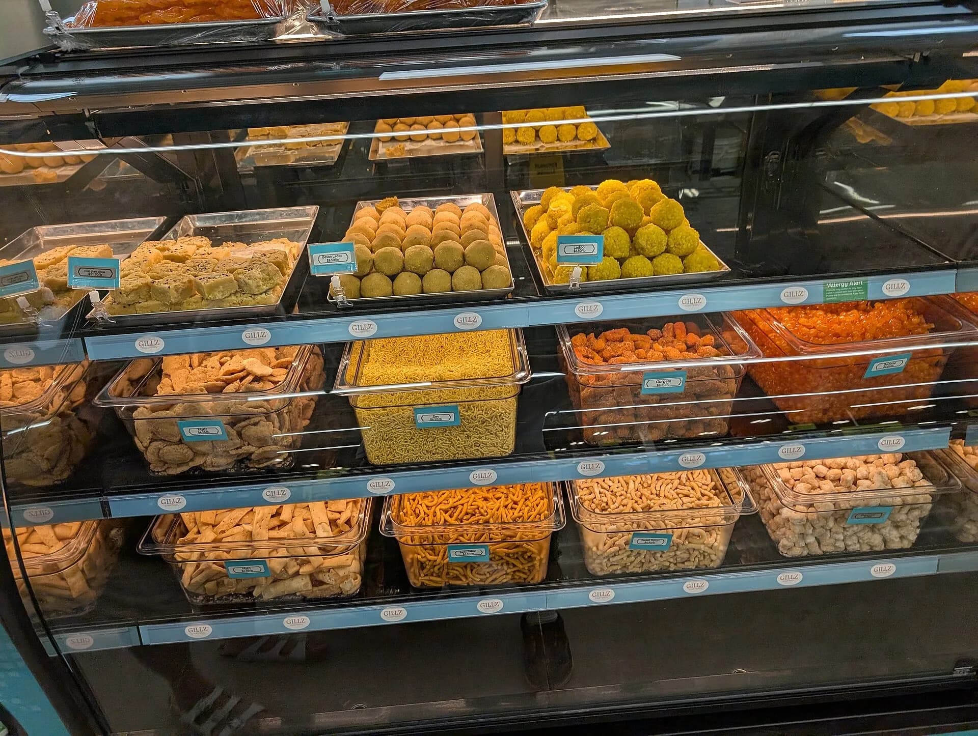 A shop display of Indian sweets in trays