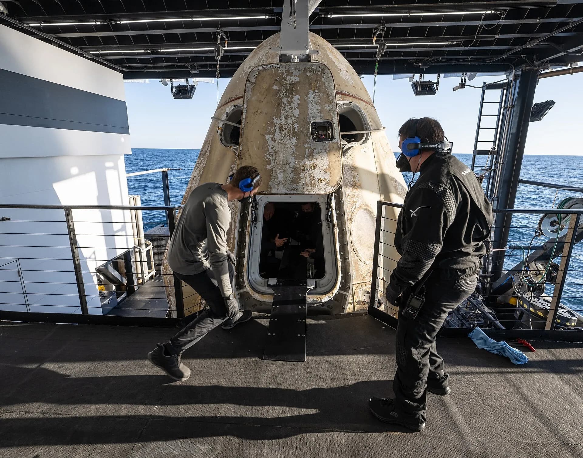 Recovery teams around a crew capsule after splashdown
