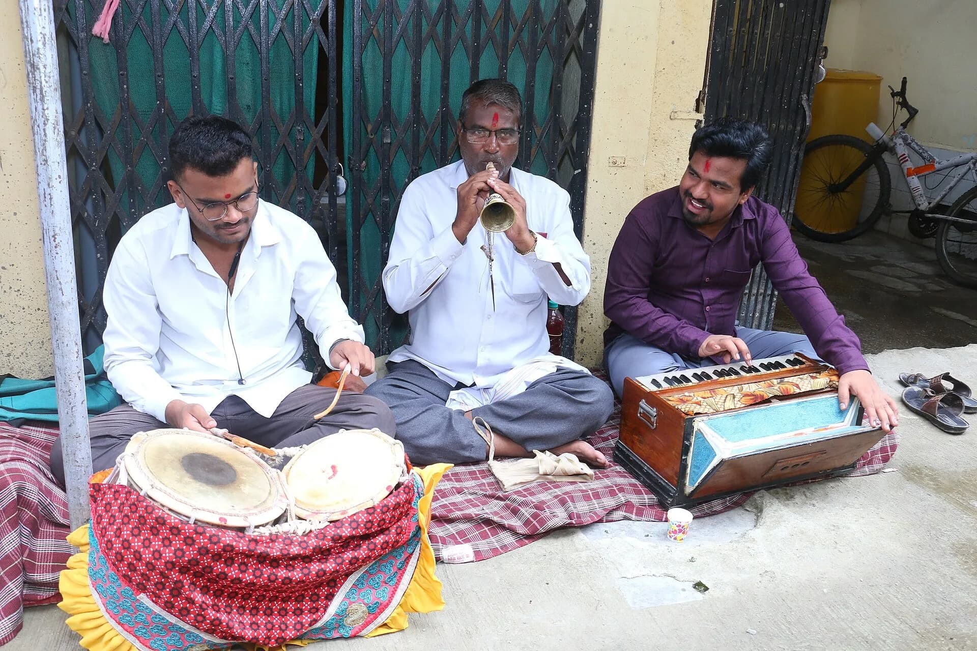 Folk musicians playing a dholak and harmonium on a street