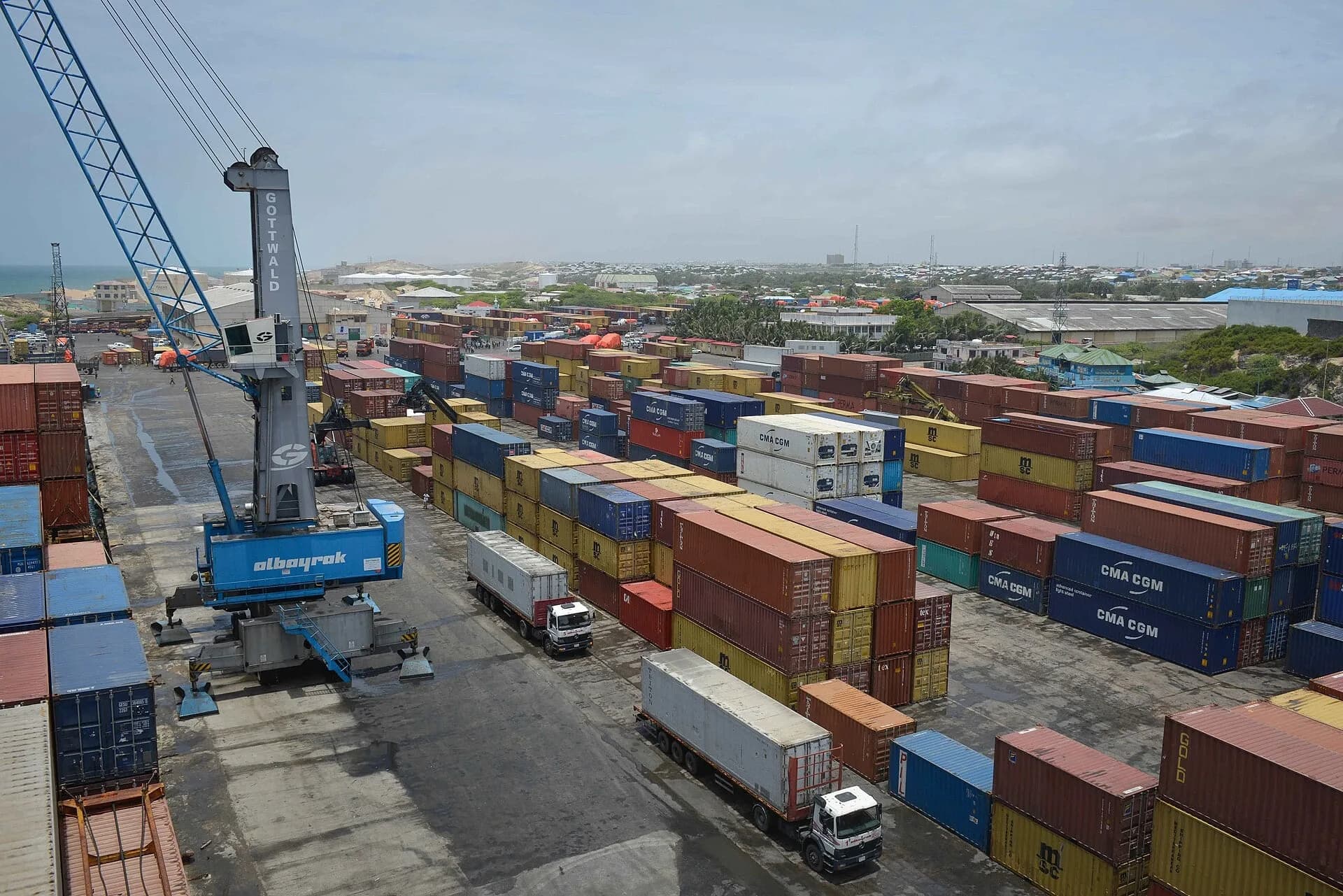 Rows of stacked shipping containers and a crane at a busy port