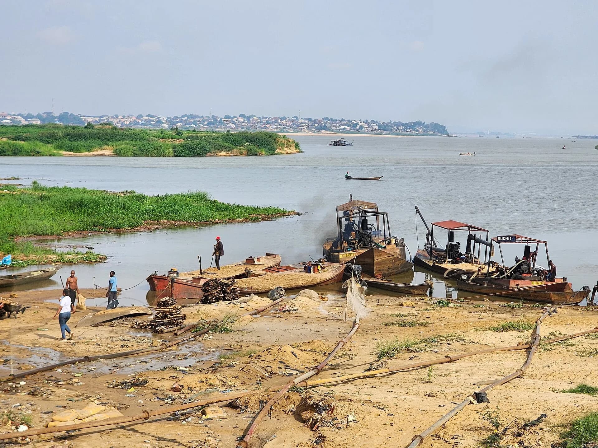 Boats and workers mining sand on a riverbank