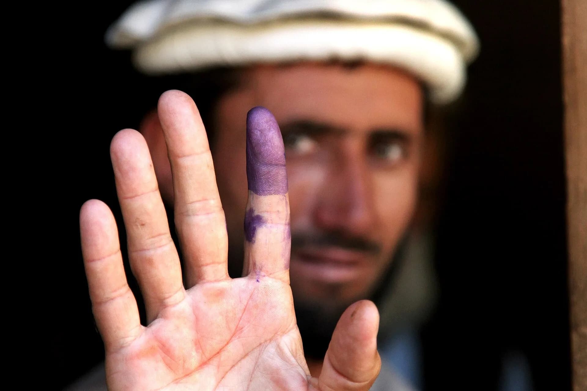 An elderly man showing his ink-marked finger after voting