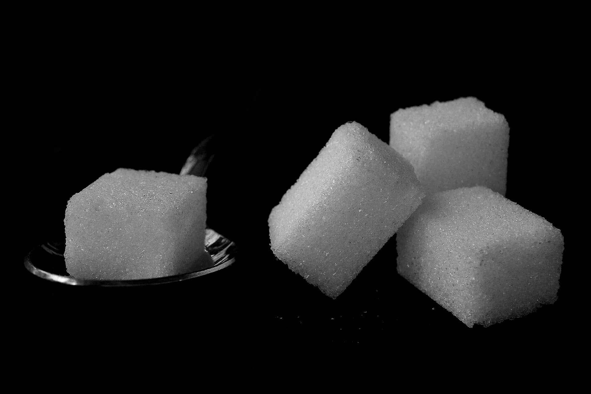 Three white sugar cubes on a dark background