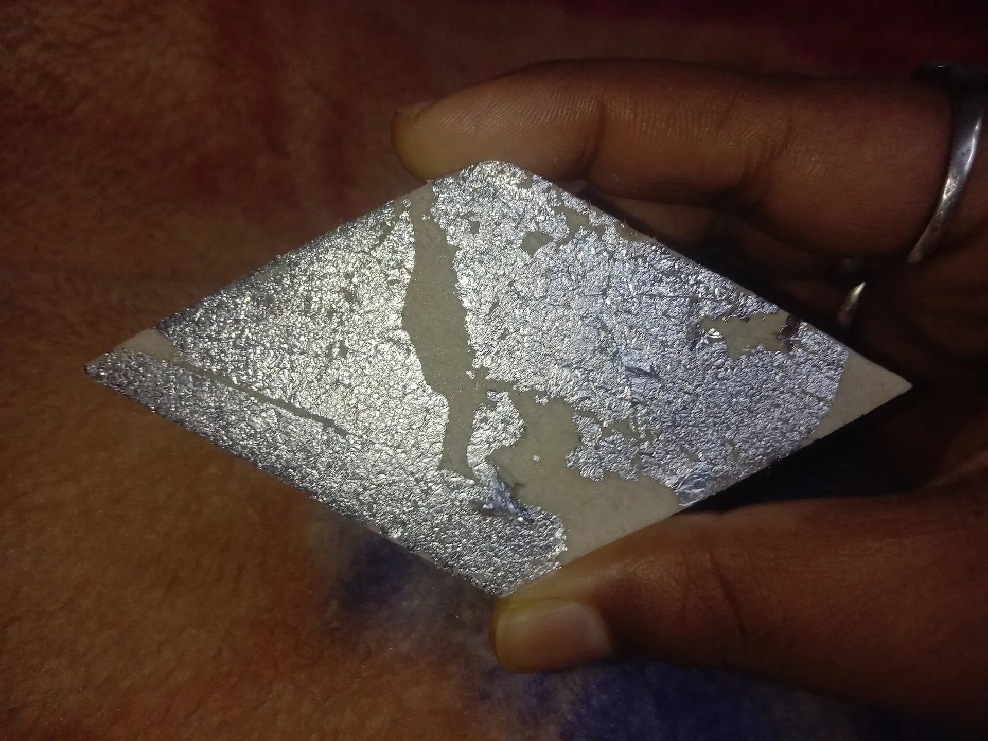 A thin sheet of silver varq held on fingertips