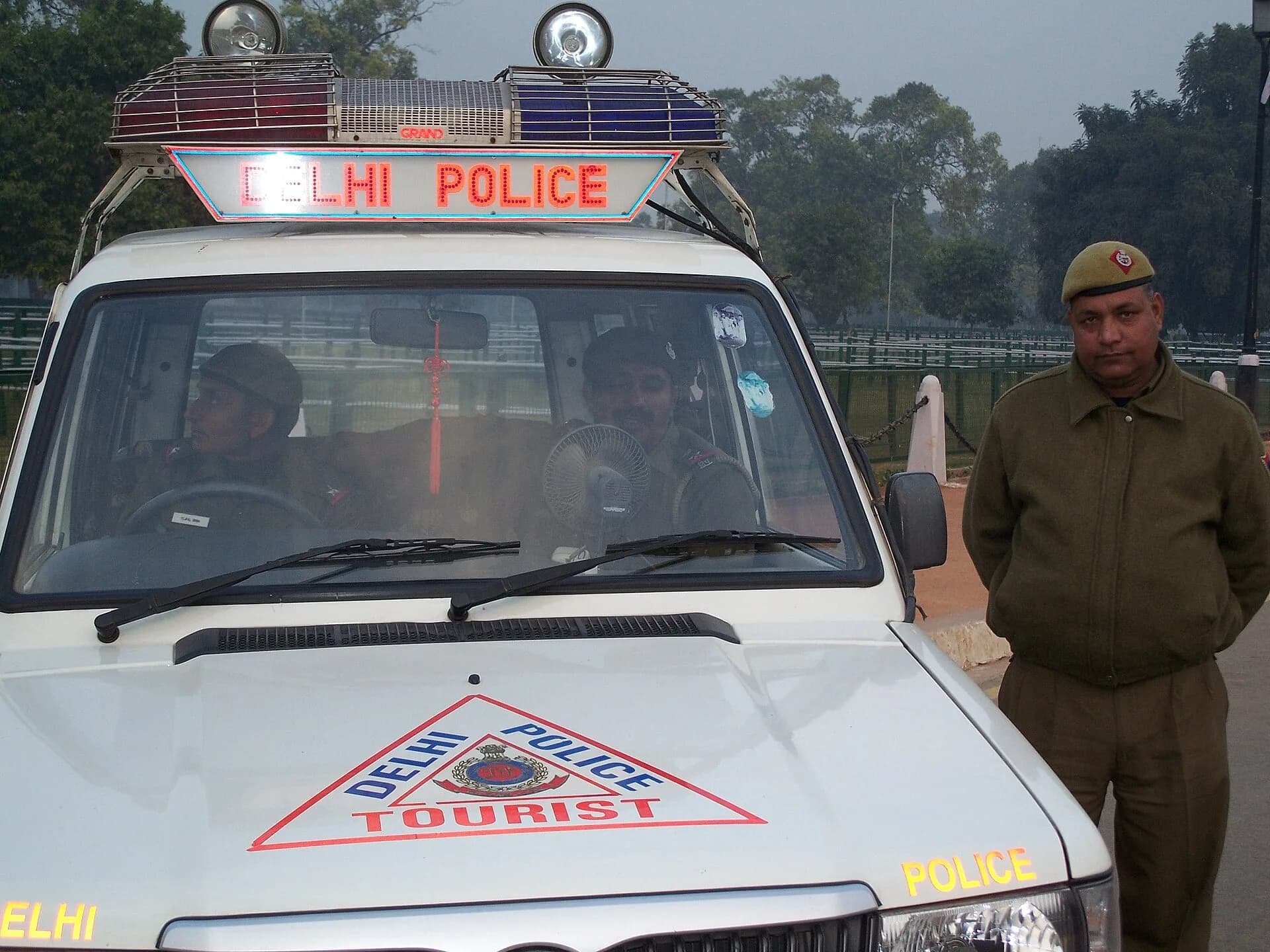 A police officer standing beside a Delhi Police vehicle