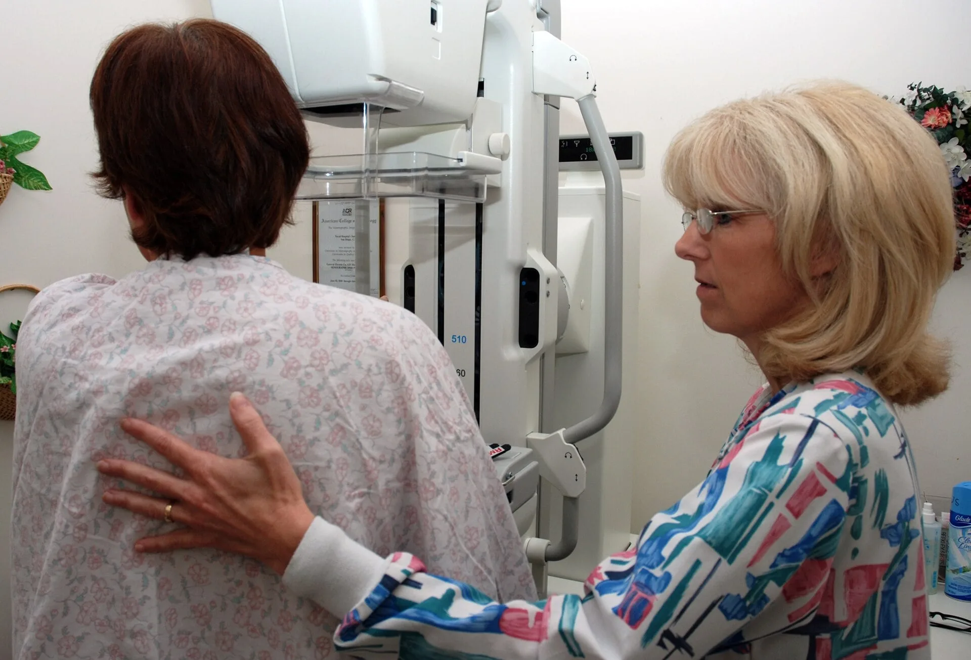 A technician helping a woman at a mammography machine