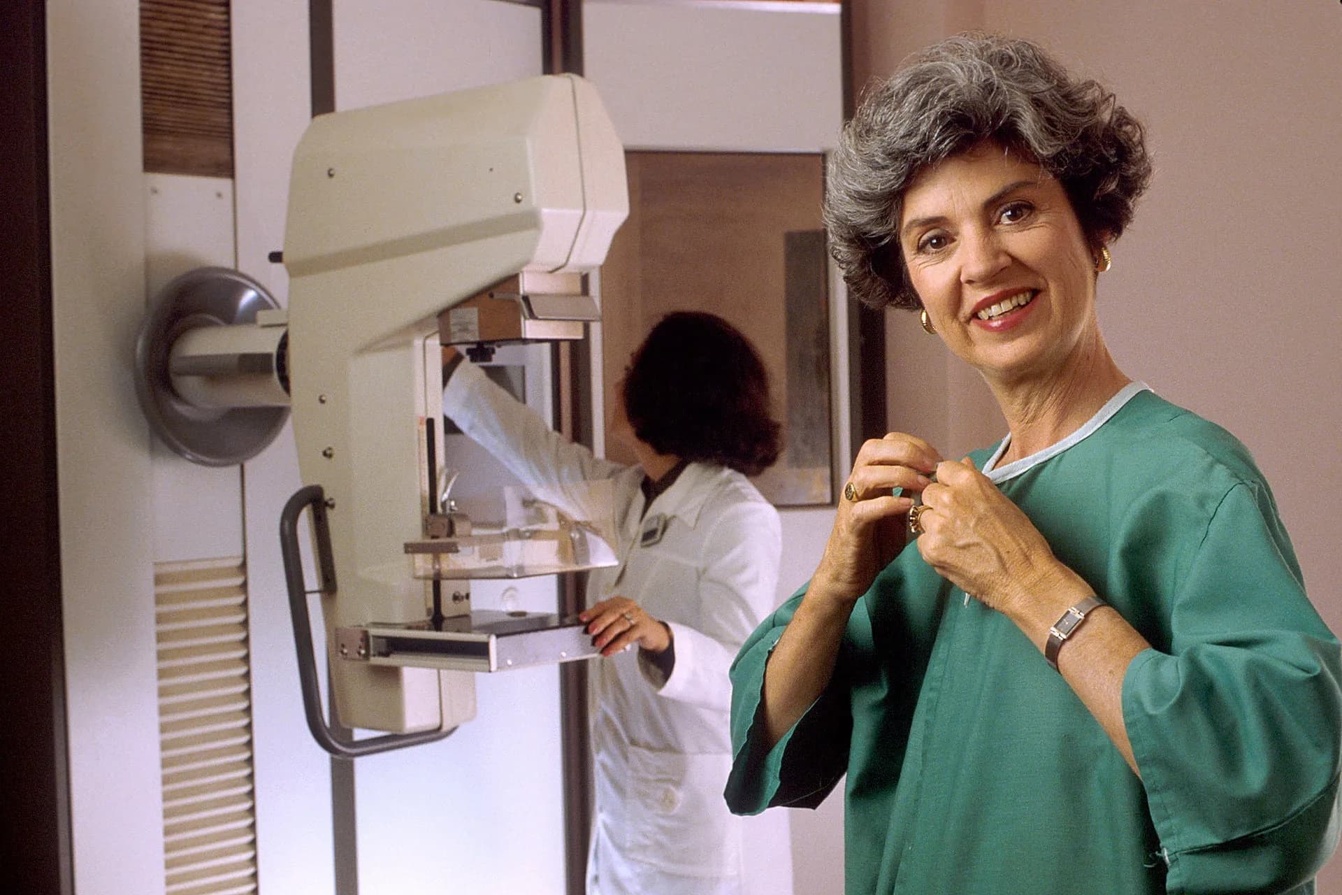 A smiling woman beside a mammography machine