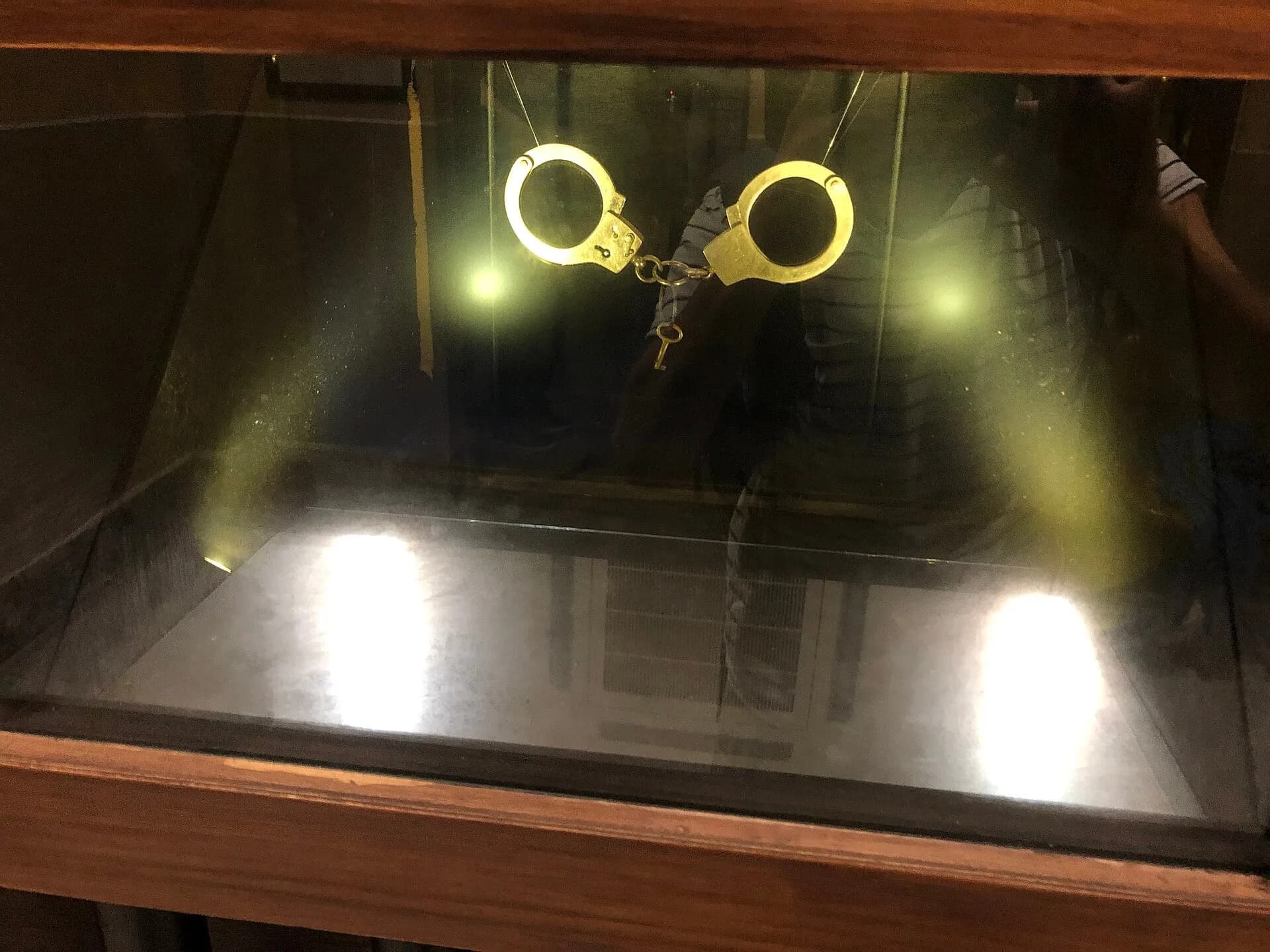 Old handcuffs and a key in a glass display case