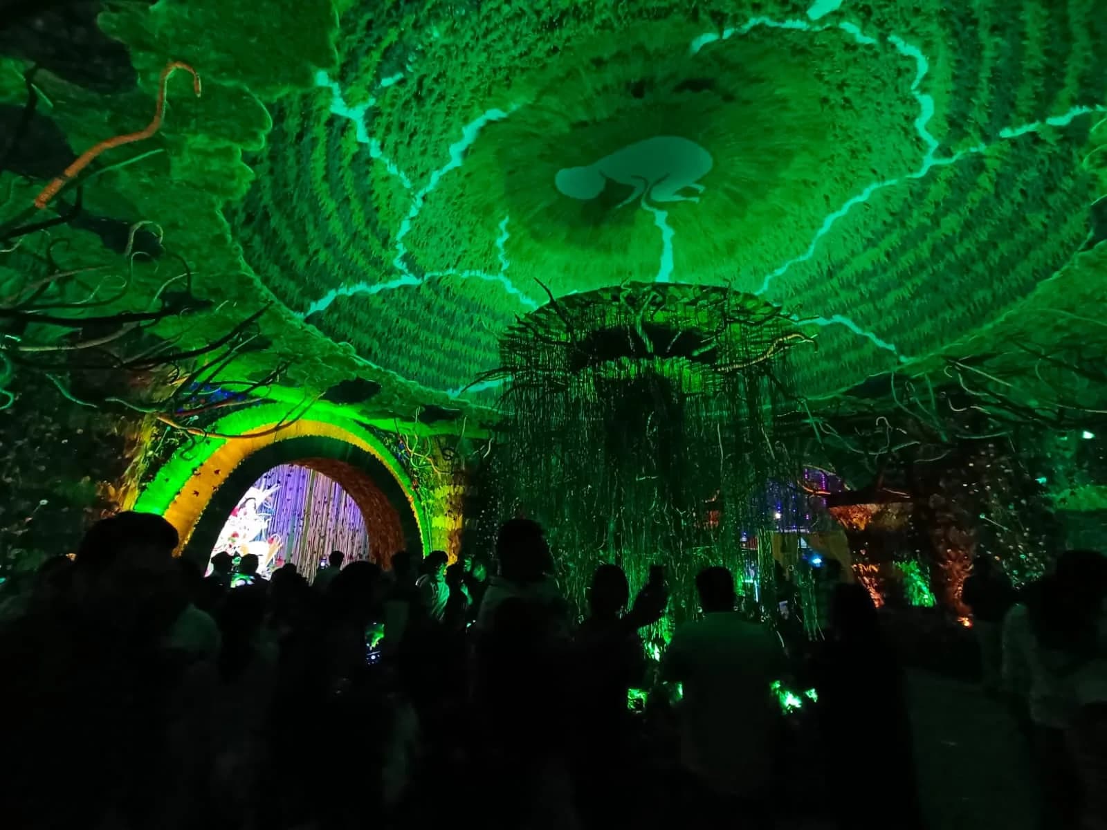 A Durga Puja pandal lit with green lights on an afforestation theme