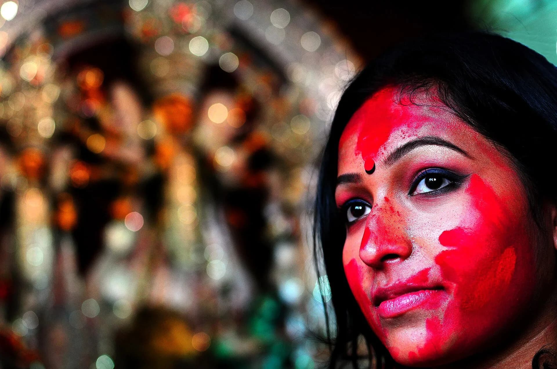 A woman with her face smeared with red sindoor during Durga Puja