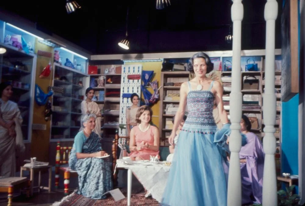 A model in a pale blue gown walks past seated women in saris at a fashion show in India in 1962