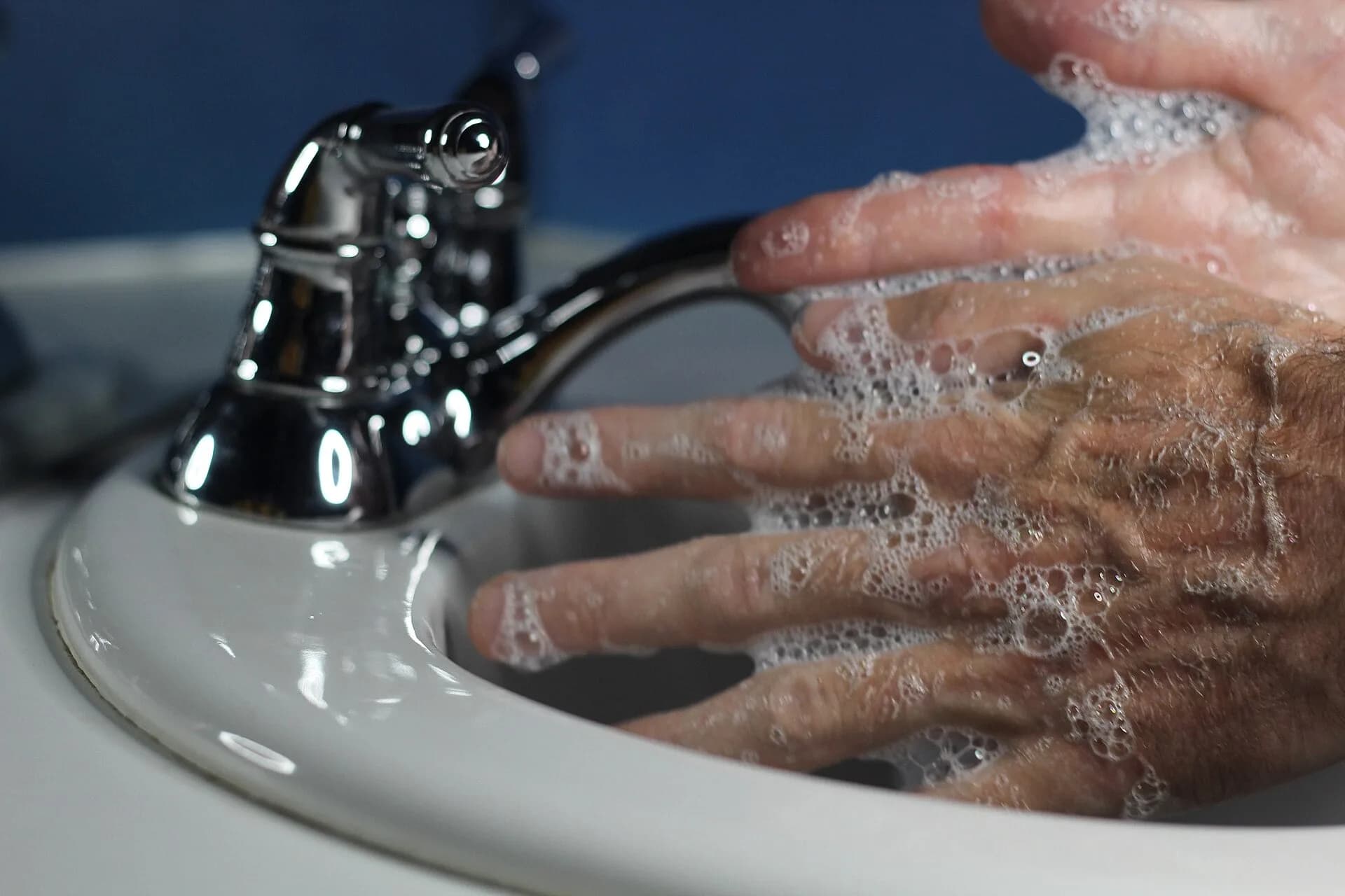 A man washing his hands with soap at a sink