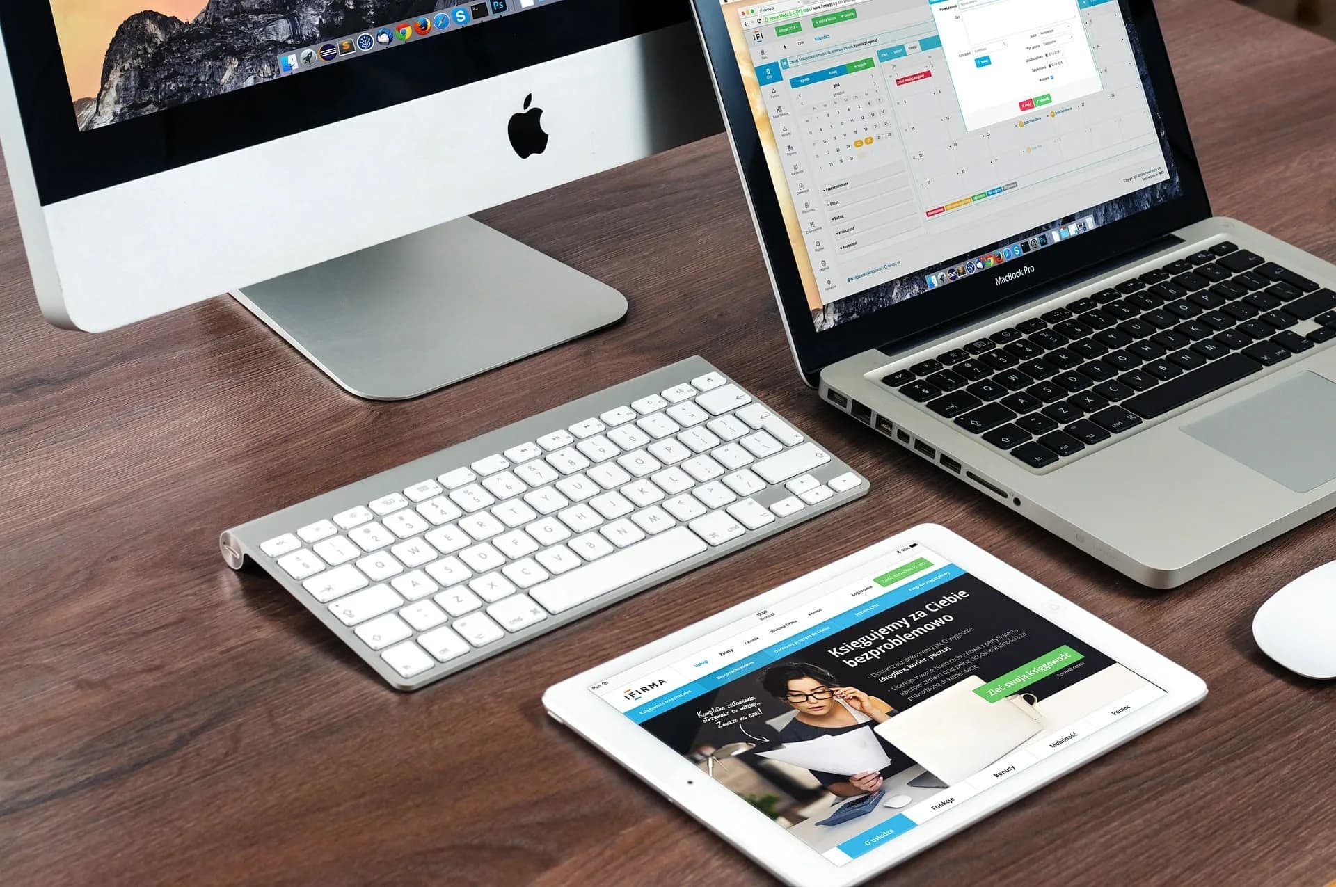 A desk with a computer, a laptop and a tablet