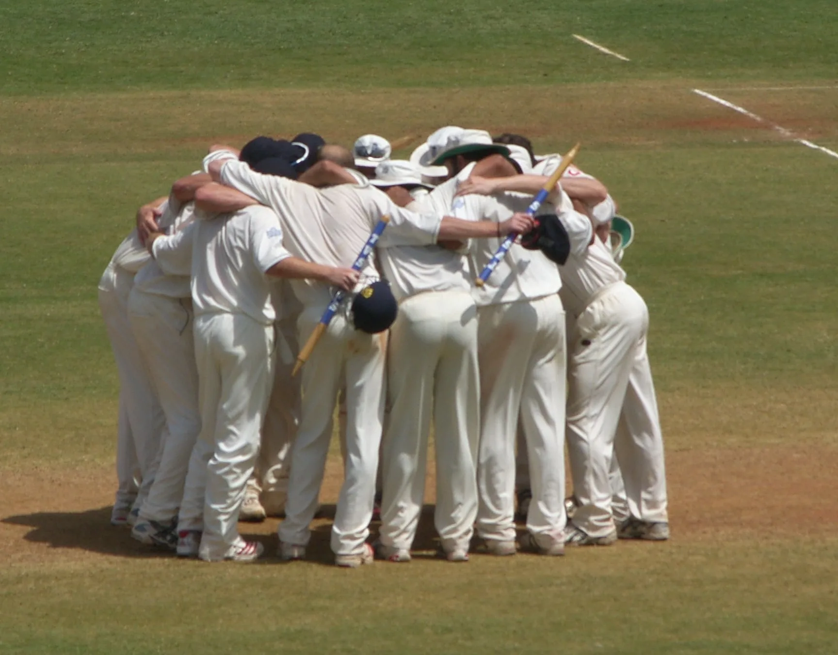 Cricketers in a team huddle on the field