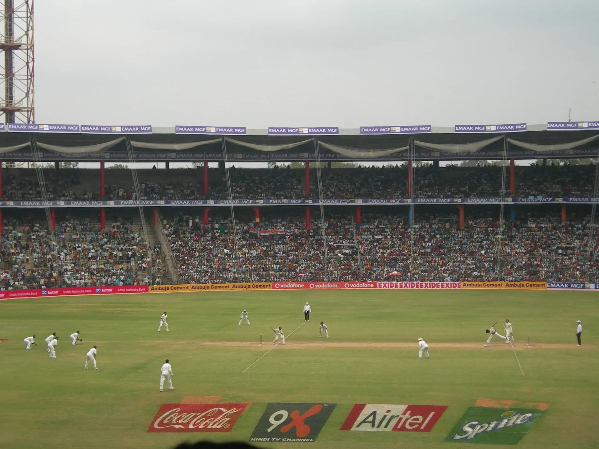 A floodlit cricket ground with advertising boards