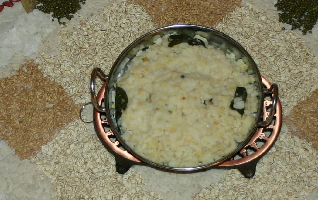 A pot of Pongal placed on a kolam with grains