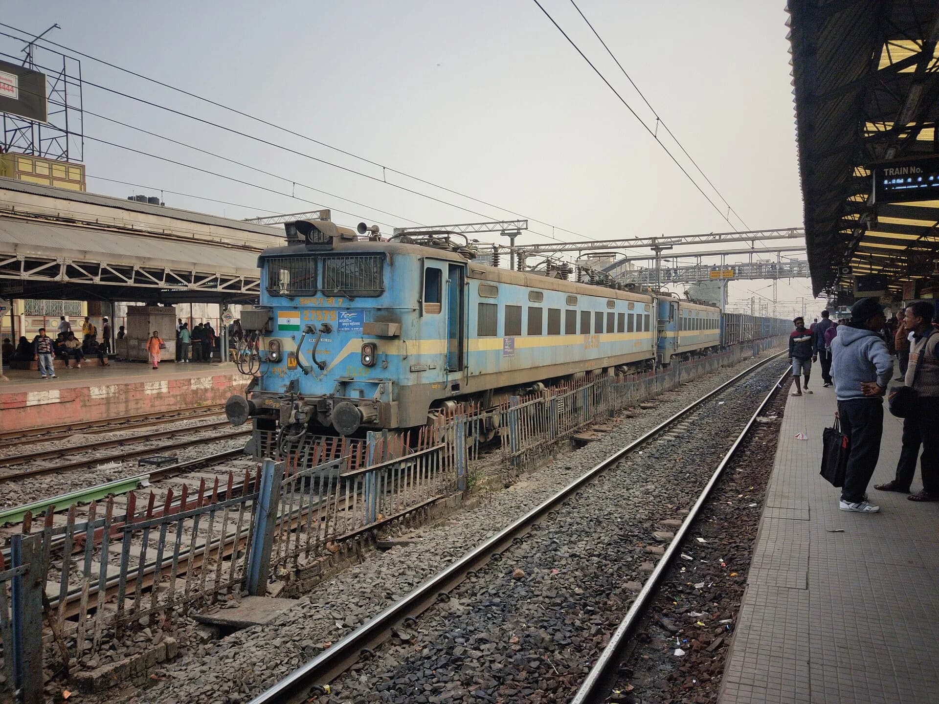An electric locomotive hauling a freight train through a railway junction in India