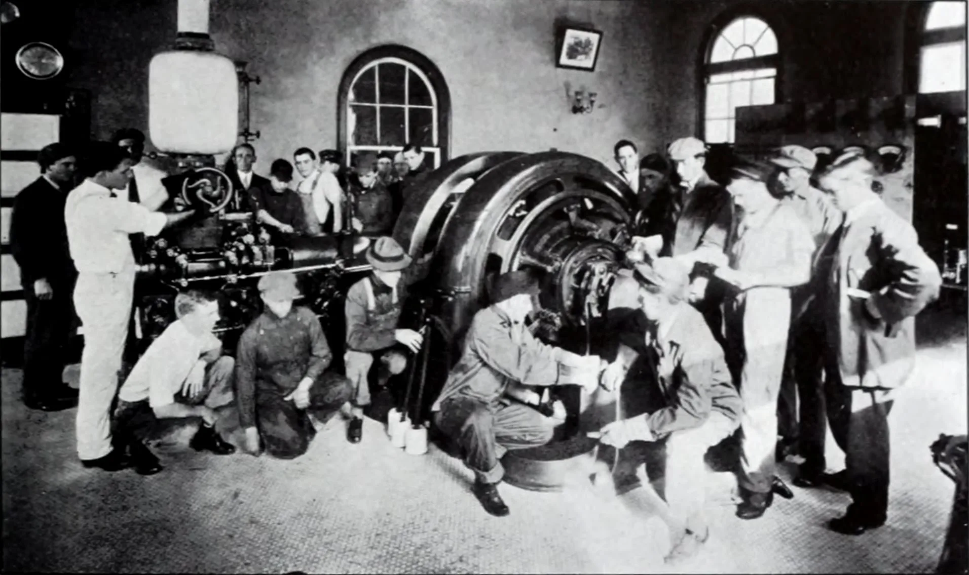 Engineering students gathered around large electrical machines in an old photograph
