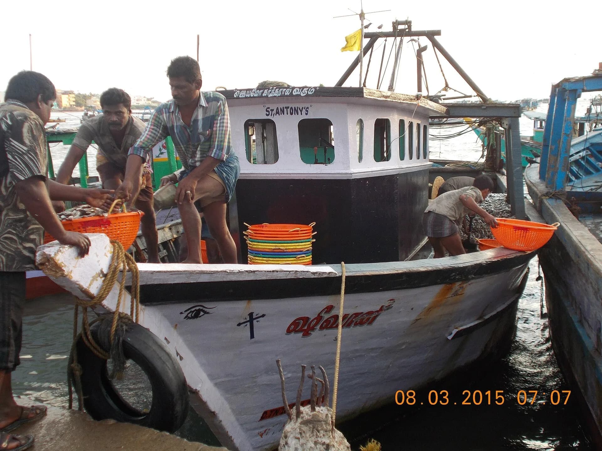 Fishermen unloading their catch from a fishing boat moored at Rameswaram port