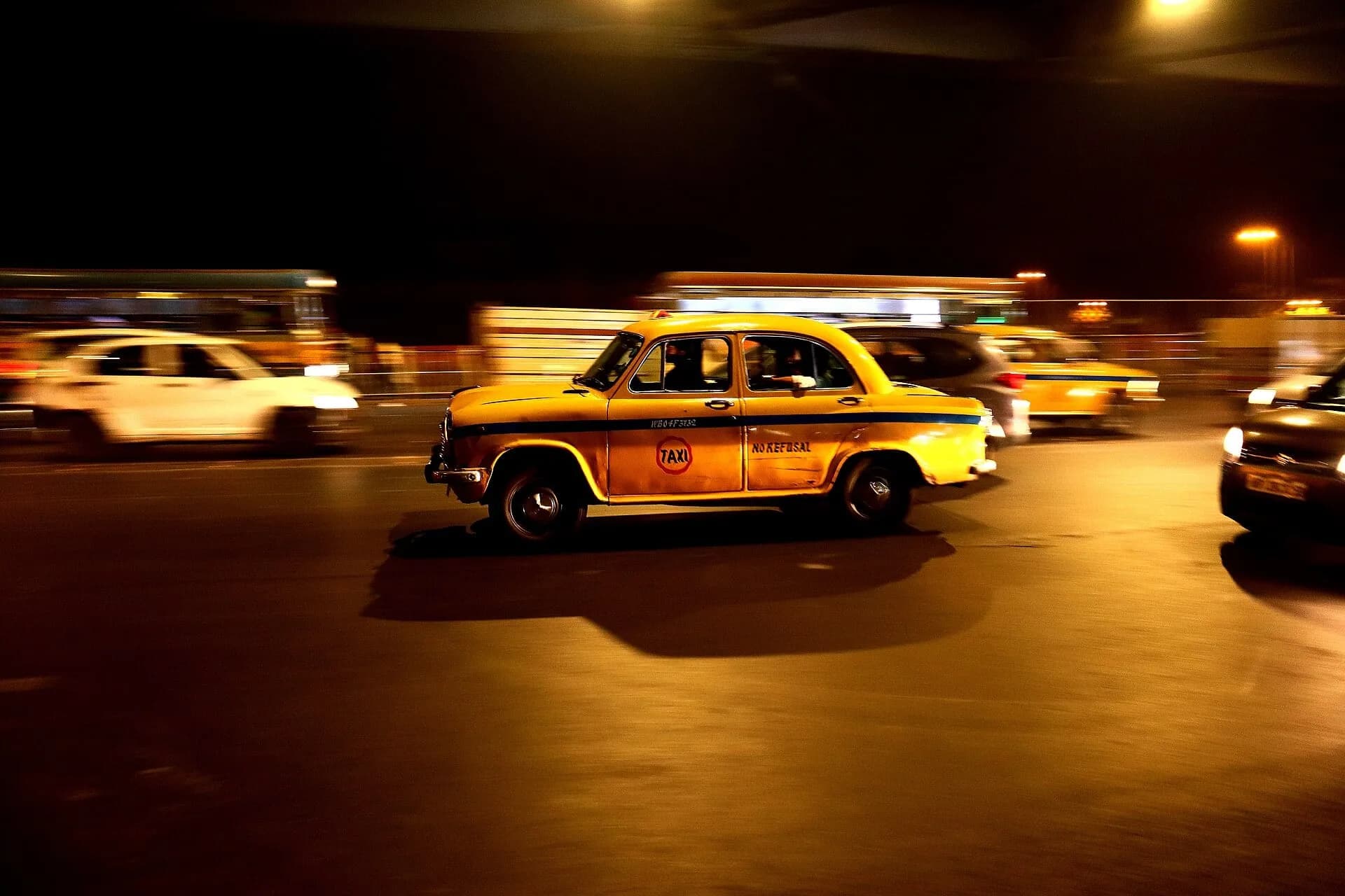 A yellow taxi on a Kolkata street at night