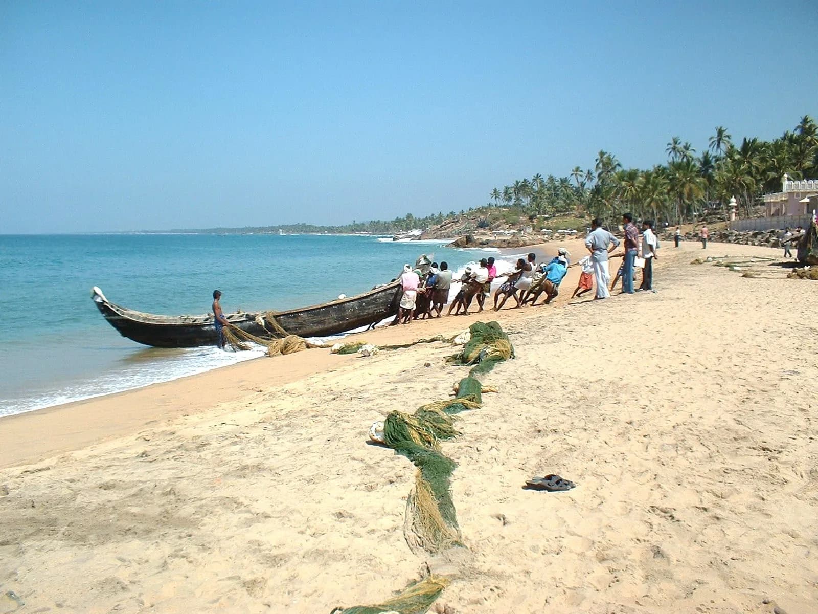 Fishermen and a fishing boat on Kovalam beach in Kerala