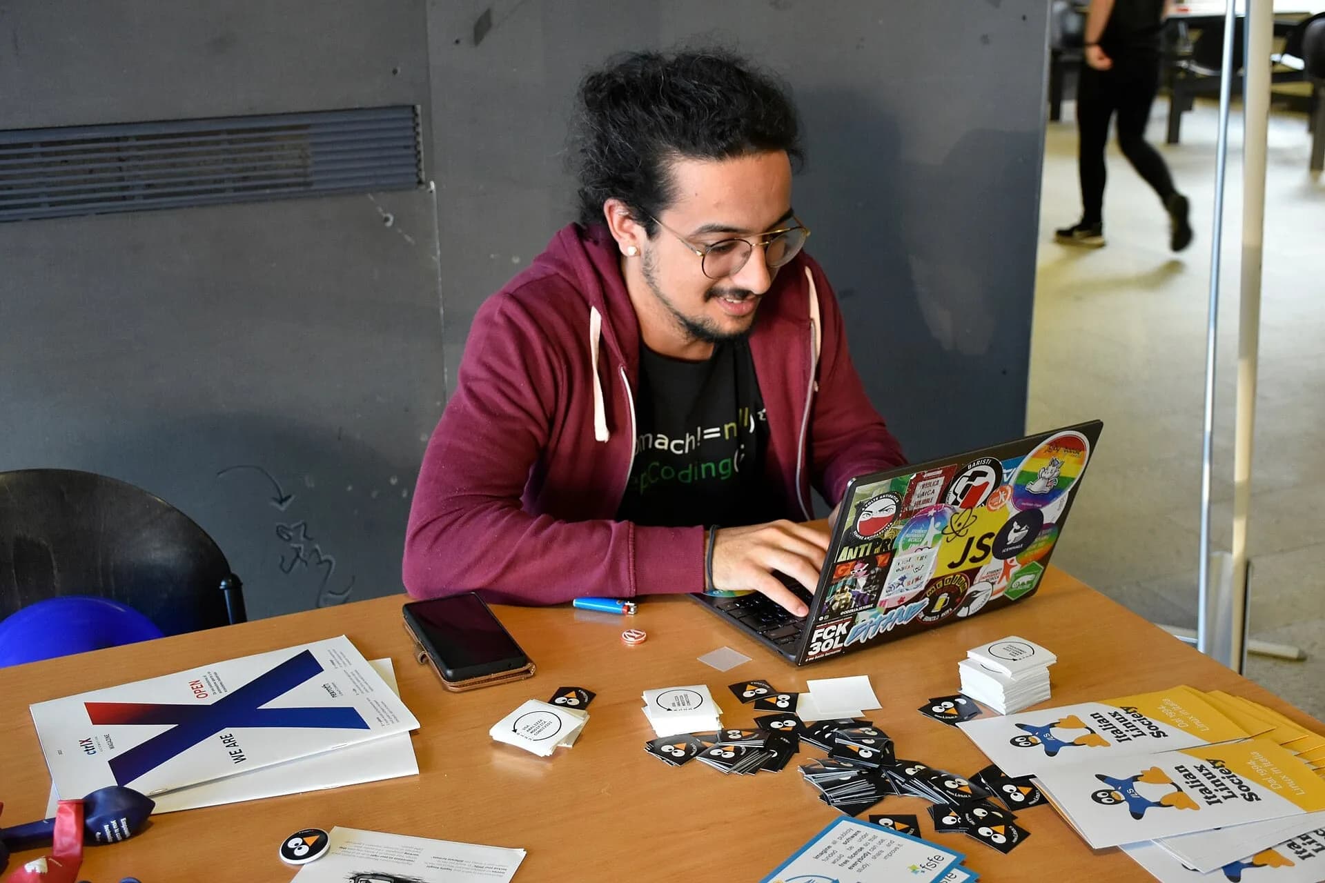 A person typing on a laptop covered in stickers