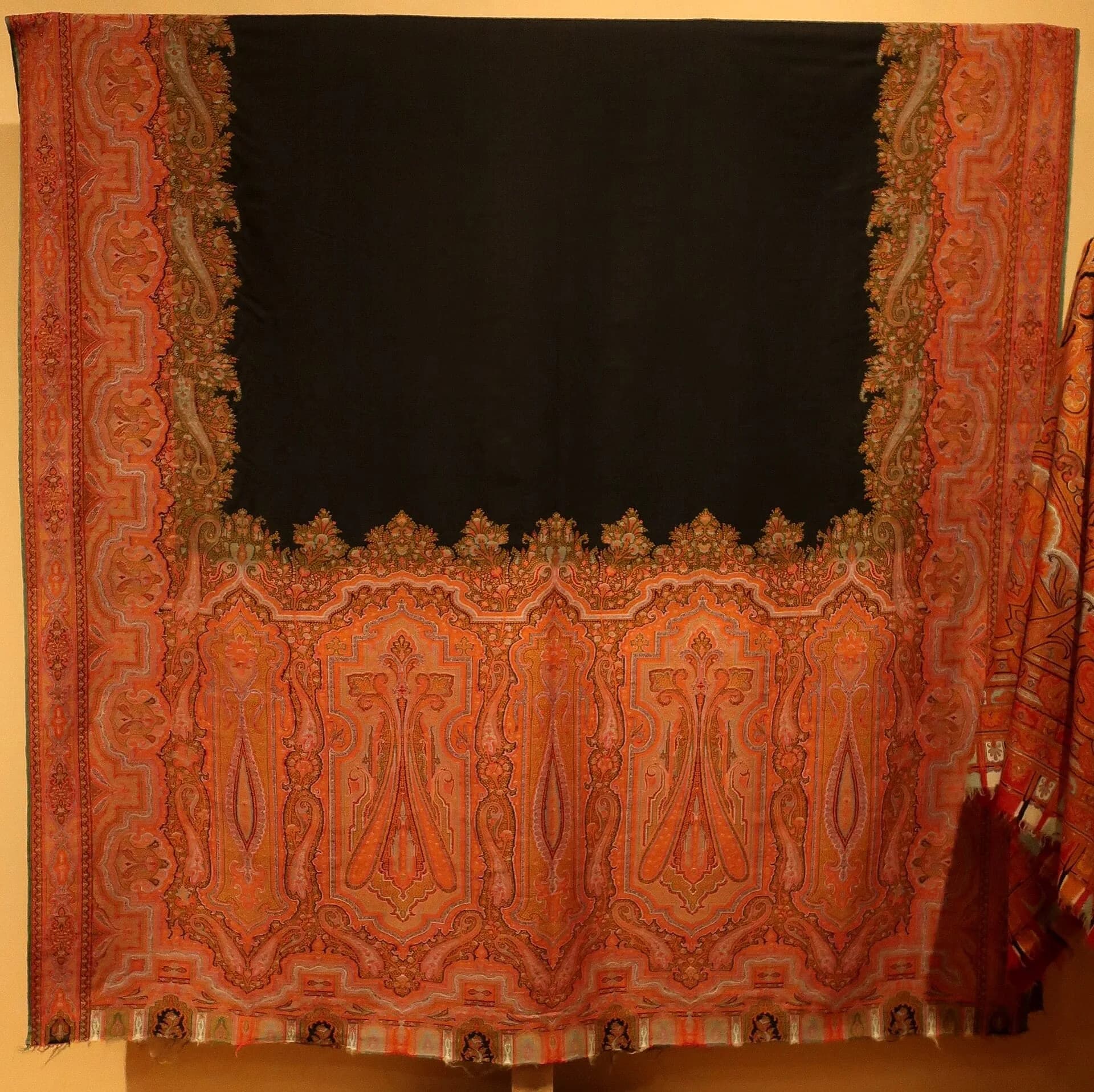 A 19th-century Paisley shawl with a black centre and a wide border of red and orange paisley motifs