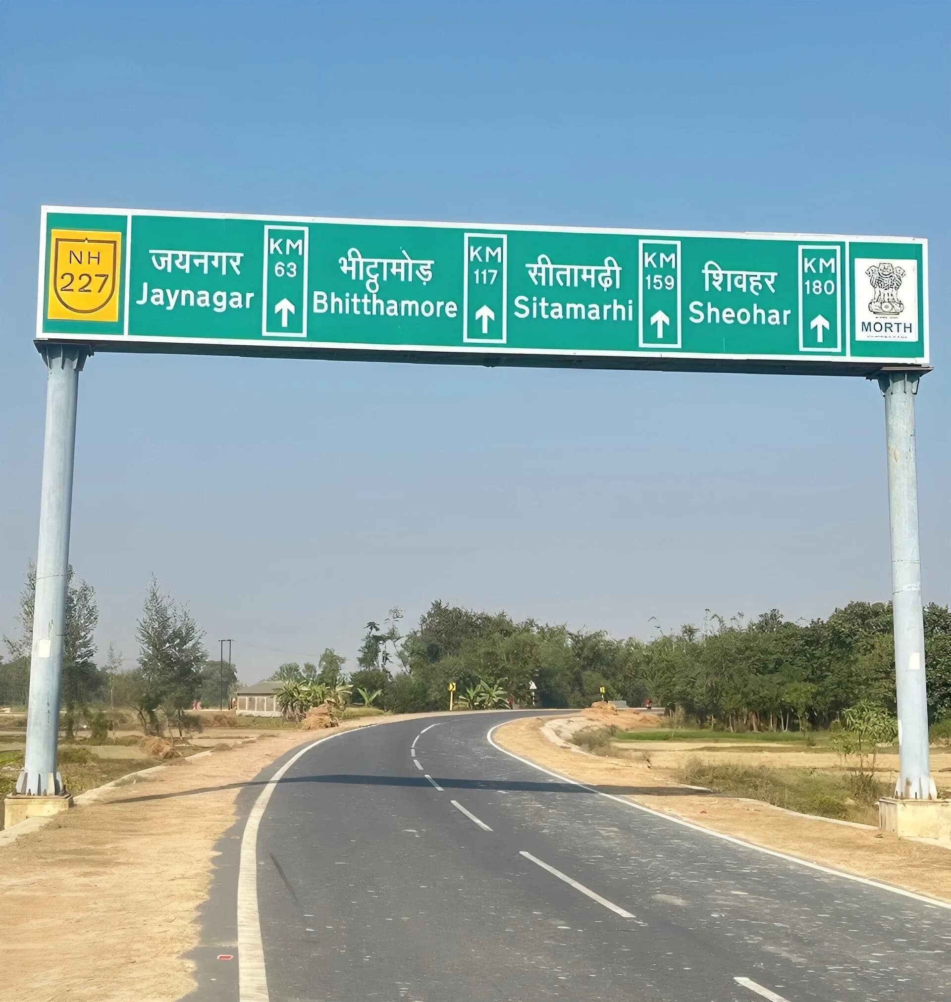 A green highway direction sign over a rural road