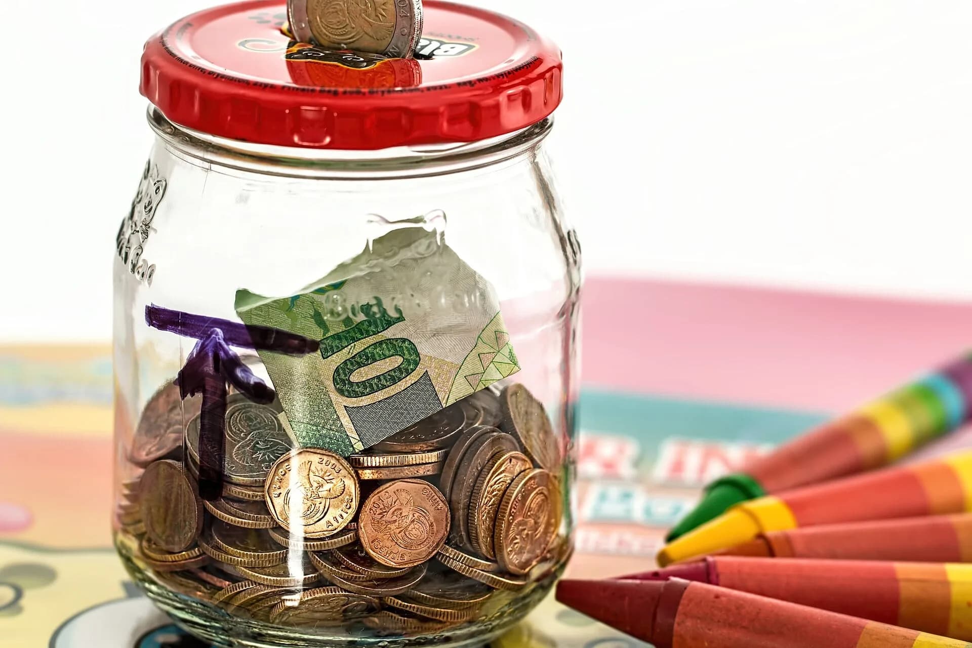A glass jar filled with coins and banknotes