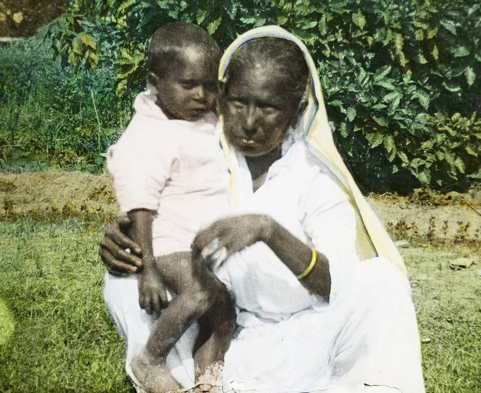 An elderly Indian woman holding a baby in an old photograph