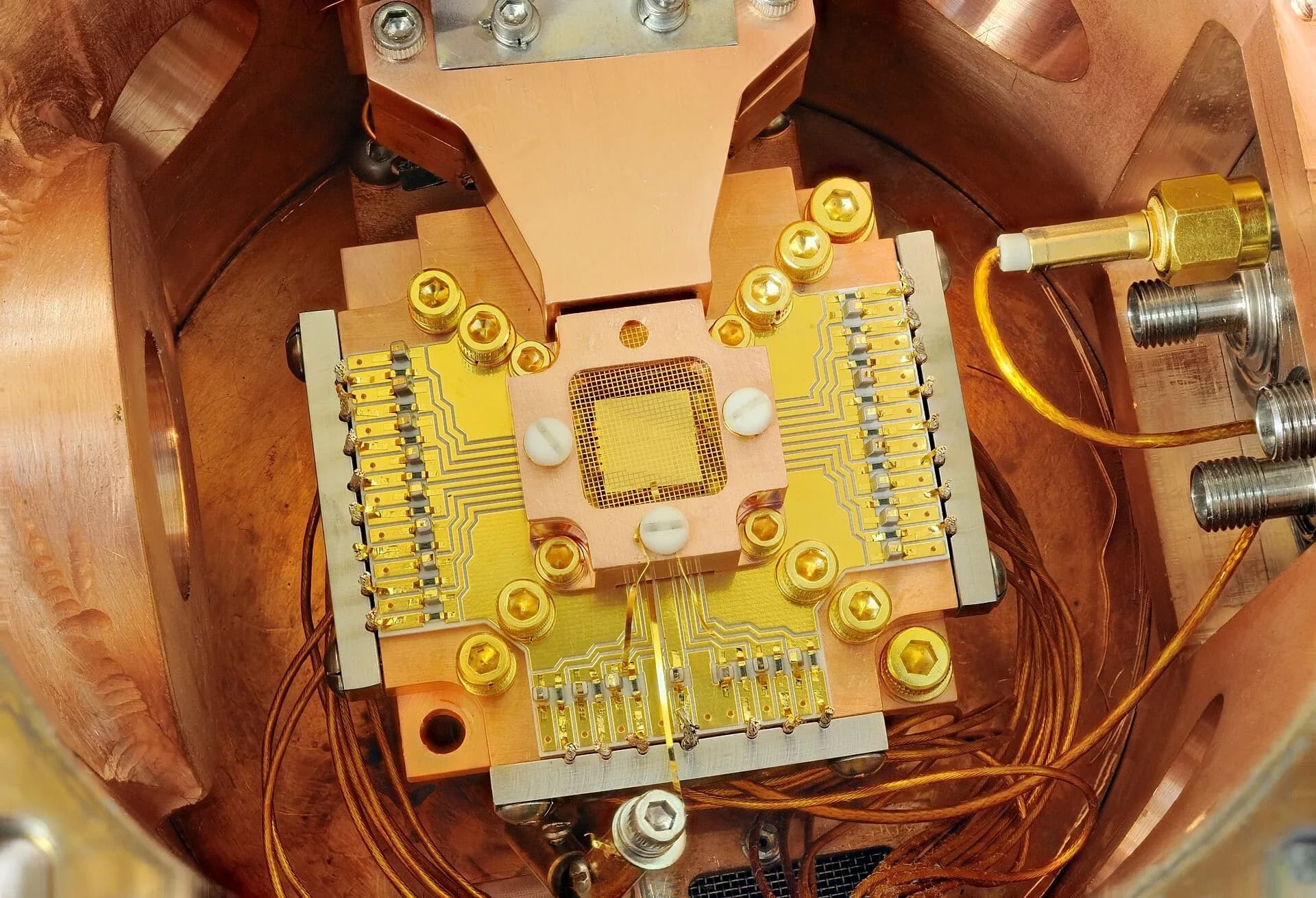 A quantum chip mounted inside a cryogenic experiment, with gold-coloured connections and copper wiring
