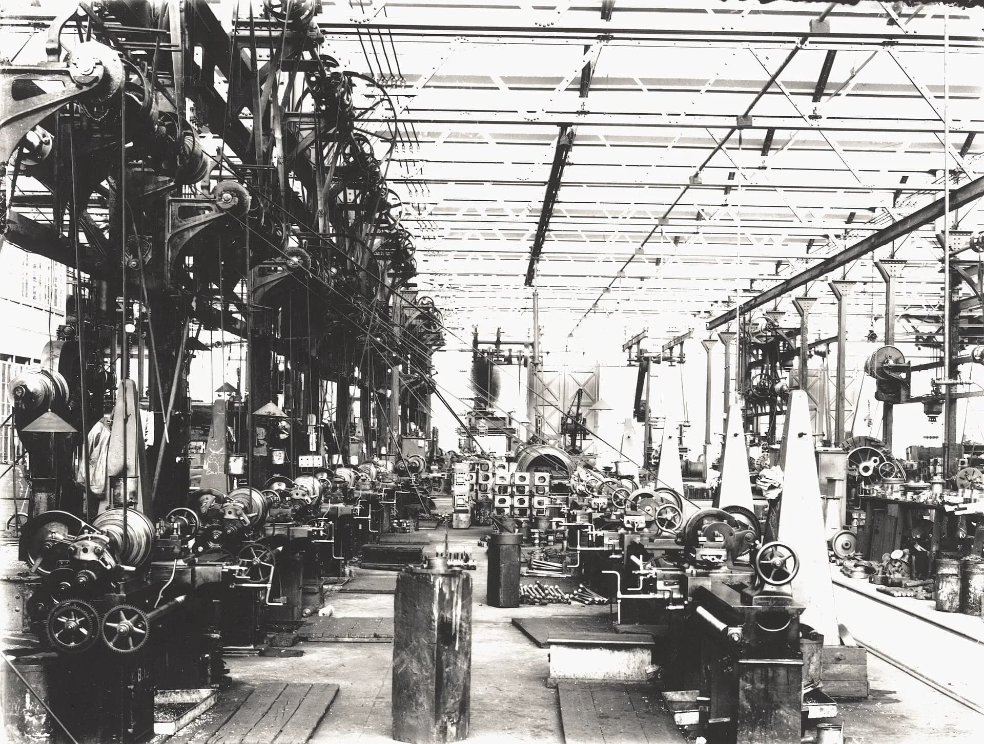A large machine shop with rows of lathes and belt-driven machinery in an early factory