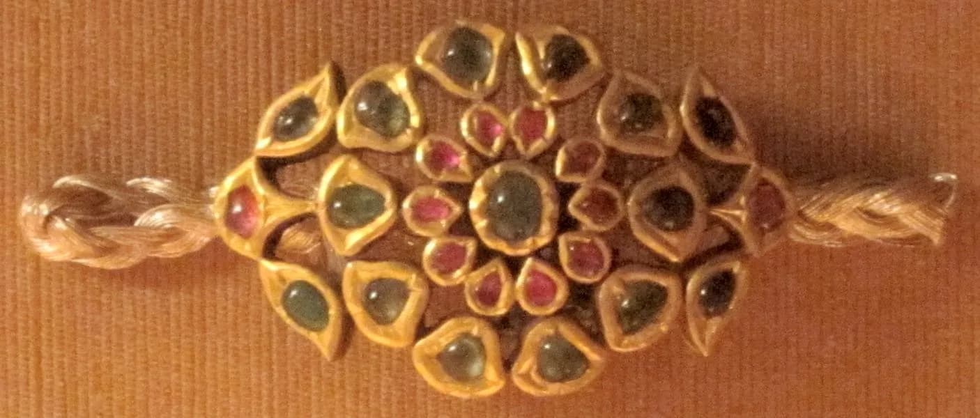 A gold arm ornament set with rubies and emeralds